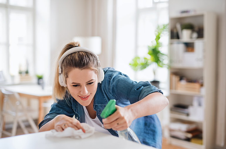 teenage girl disinfecting a countertop in her home